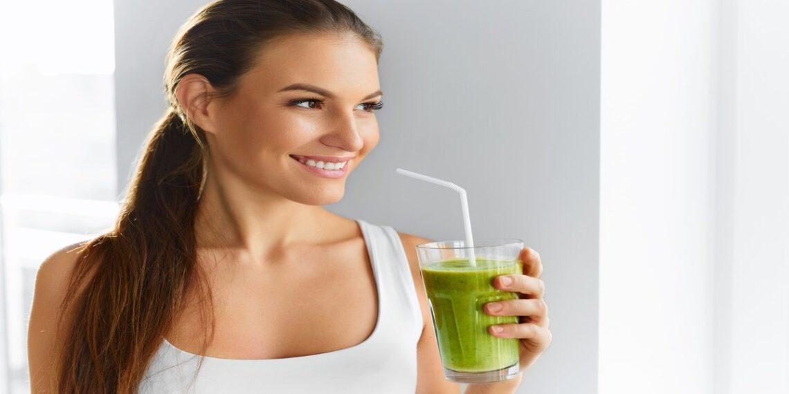 woman drinking a green smoothie